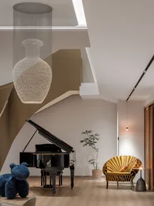 A modern living space featuring a luxurious leather couch, stylish light fixtures, and a functional desk area with a computer