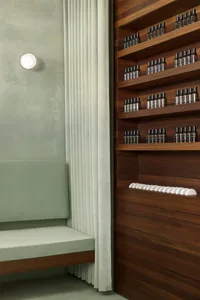 Modern minimalist spa interior with wooden shelves displaying bottles and white curtains