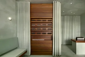 Modern minimalist storefront with concrete walls, wood cabinetry, concrete floors, and a white curtain.