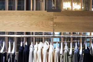 A clothing store display featuring wooden and metal elements with hanging rails holding various garments.