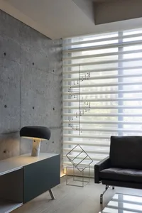 Minimalist living room with concrete walls, glass window, and modern furniture.