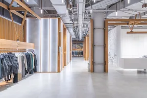 An interior shot of a modern clothing retail store with wooden frames and concrete walls showcasing contemporary design eleme