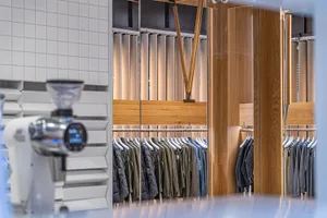Clothing store interior with modern design featuring wooden shelves and hanging racks.