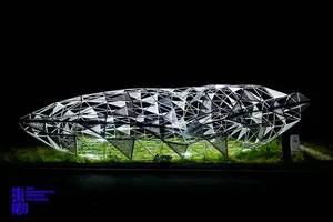 A modern, geometric, metal structure with a meshed exterior.