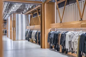 A modern retail clothing store with minimalist design featuring wood and concrete materials.