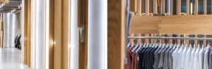 Modern retail store with wooden walls and a hanging rail displaying casual clothing.