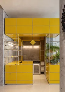 Modern kitchen with modular yellow metal cabinets and concrete backsplash.