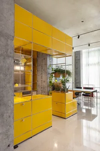 A vibrant yellow office space featuring metallic furniture and concrete walls.