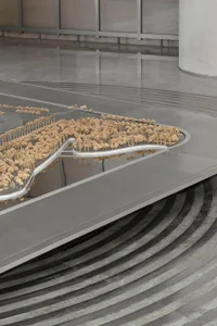 Detailed architectural model with miniature trees and curved surfaces in a contemporary setting.