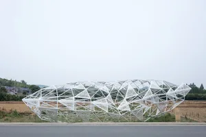 A modern, white metal frame structure in an open field.