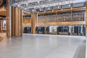 Modern clothing retail shop featuring wooden racks and clothing items displayed on them.