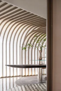 A modern interior space with glass walls and a polished floor, featuring a sleek table and decorative plant.