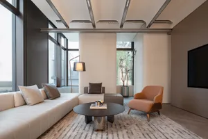 Contemporary living room featuring modern furniture with soft, textured fabric upholstery, large windows with views of the ou