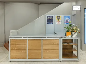 Modern reception desk with wooden drawers and metal frame, accompanied by potted plants.