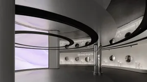 A modern shopping center exhibit space with curved metallic structures and glass elements.