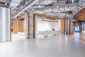 A modern interior of a shopping mall with clean lines, white floors, and wooden accents.