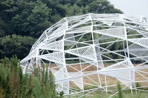 A modern geometric structure with a metallic, perforated framework.