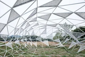 A large, intricate metal structure with a geometric pattern, possibly an outdoor art installation.