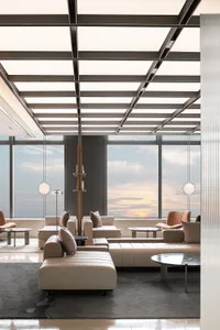 Modern industrial-style lobby with metallic ceiling, glass windows, and leather seating.