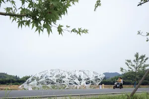 白色金屬雕塑帶有幾何圖案，置於道路上。
