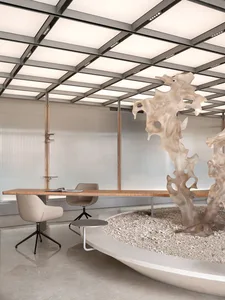 A minimalist office space featuring a concrete desk and chairs, with a large abstract sculpture in the center of the room.