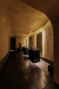 A modern, industrial-style bathroom with concrete walls and floors, featuring sleek black fixtures and warm, ambient lighting