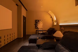 A cozy home theater with minimalist design, concrete flooring, and black furniture.