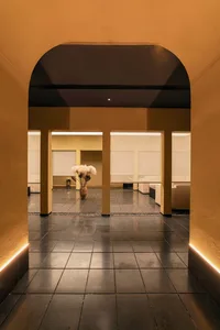 A minimalist interior space with black tiles and concrete elements, featuring a vase of white flowers.