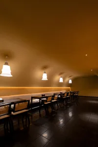 A cozy, modern restaurant interior with wooden furniture and pendant lights.