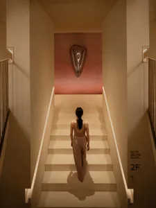 A woman walking up a white staircase with a metallic shield wall art above her.