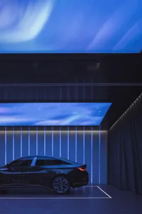 Black sedan parked in a modern garage with LED lighting displaying an abstract sky
