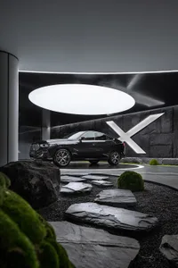 Modern car dealership interior with black metal accents and a sleek black car on display.