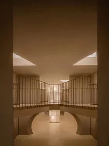 A minimalist interior space featuring minimalist concrete architecture with natural light entering through skylights.