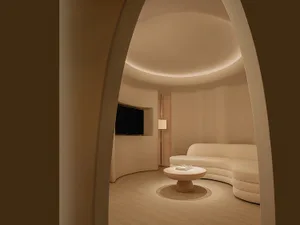 A minimalist living room with a curved sofa in textured cloth and a round coffee table.