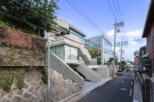 Modern minimalist residential architecture featuring glass walls and concrete stairs.
