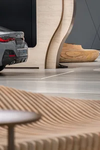 Modern showroom with concrete elements showcasing a sleek car and contemporary seating.