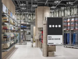 A minimalist retail shop with marble columns, glass ceilings, and metal clothing racks.
