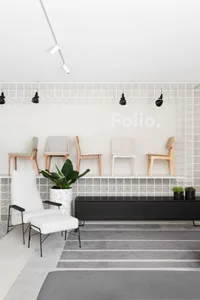 A minimalist retail shop with white-tiled walls and a black storage unit.