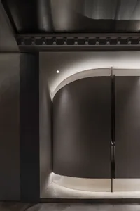 A minimalist interior design space featuring metal elements and curved walls.