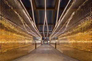 A modern art deco corridor featuring a metal mesh design, illuminated by a grid of neon lights.