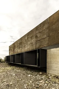 A modern concrete building with a minimalist design, featuring large windows and a clean, uncluttered appearance.