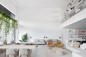 A modern minimalist living room with white walls, furniture, and green plants.
