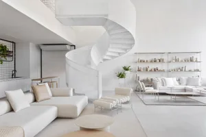 A modern minimalist living room with a white spiral staircase, concrete floor, and white furniture.