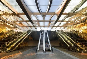 People walking on metallic-tiled escalators in a modern public space.