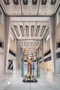 A wooden sculpture stands prominently in the center of a modern shopping center lobby.