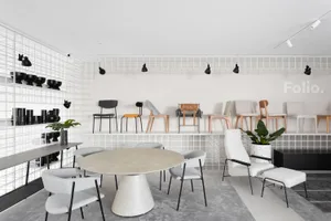 Modern showroom interior with metal shelving, fabric seating, wooden chairs, and concrete table