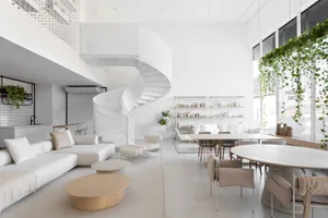 A modern living room with white cement walls, minimalist furniture, and green plants.