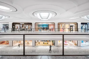 Shopping mall interior with white marble floors and walls, featuring luxury retail storefronts with glass fronts against roun