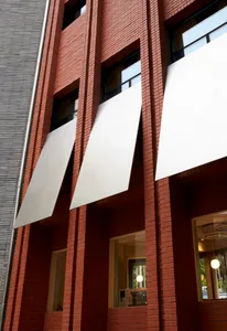 Modern brick building exterior with white awnings and glass windows.