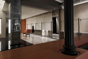 A minimalist clothing retail store featuring metallic display racks and a concrete floor.